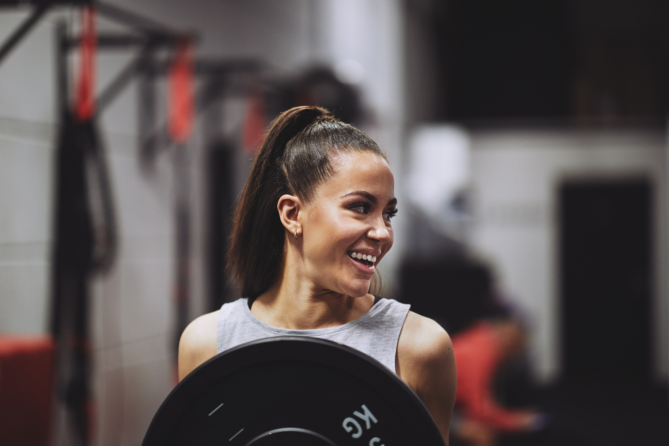 Smiling Woman Lifting Weights in the Gym